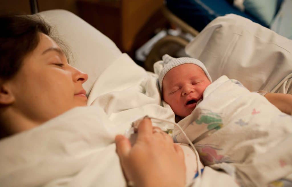 mother-holding-newborn-baby-boy-in-hospital-bed